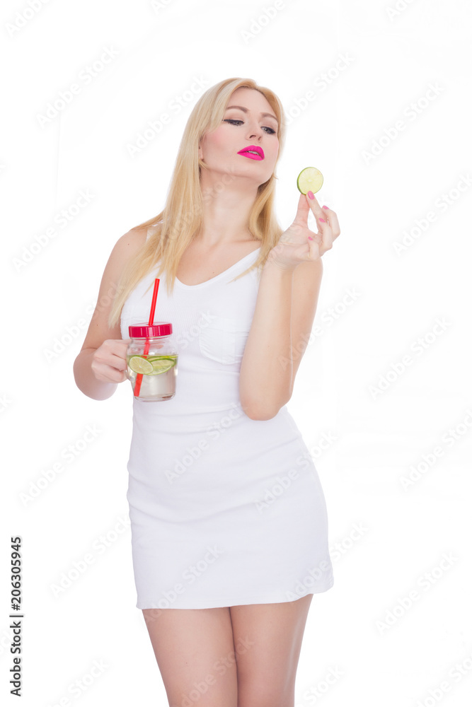 A woman on a white background holds a glass with lemonade in one hand, and in the second hand holds a piece of lime A woman on a white background holds a glass with lemonade in one hand, and in the second hand holds a piece of lime