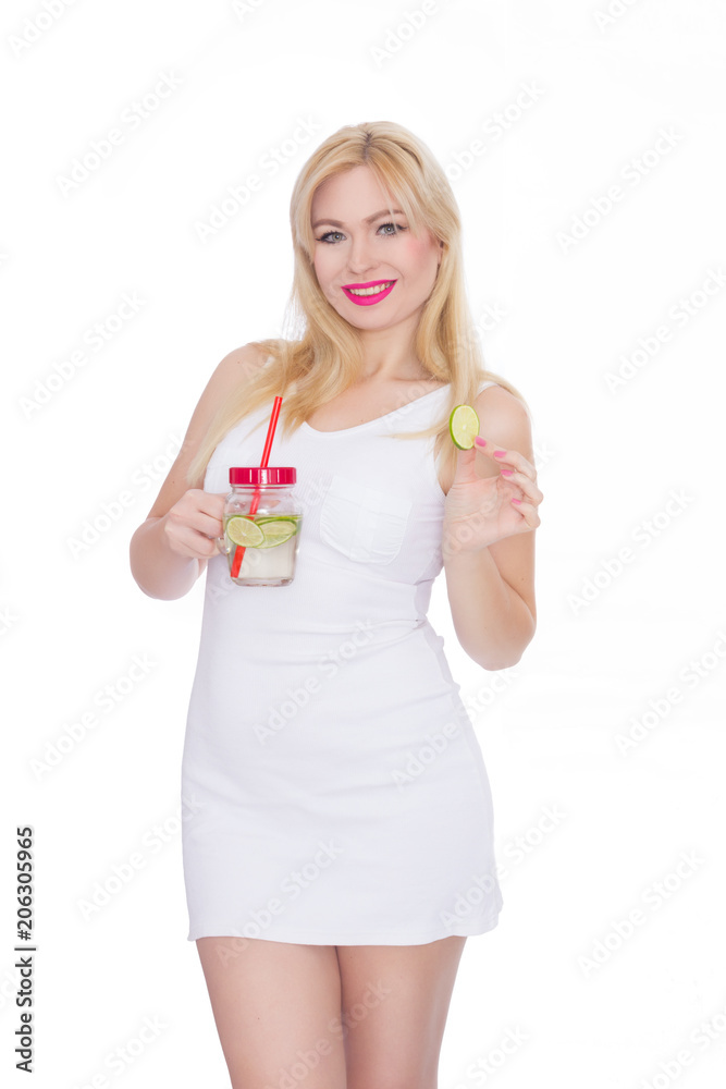 A woman on a white background holds a glass with lemonade in one hand, and in the second hand holds a piece of lime A woman on a white background holds a glass with lemonade in one hand, and in the second hand holds a piece of lime