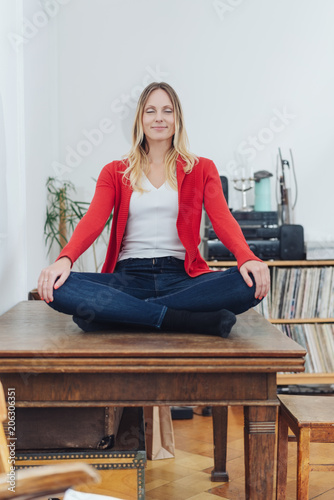 Serene young woman meditating at home