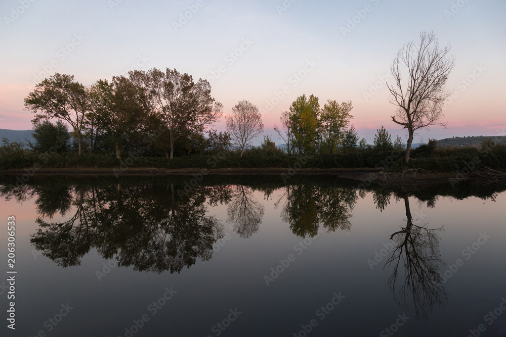 A symmetric photo of a lake, with trees and clouds reflections o A symmetric photo of a lake, with trees and clouds reflections o