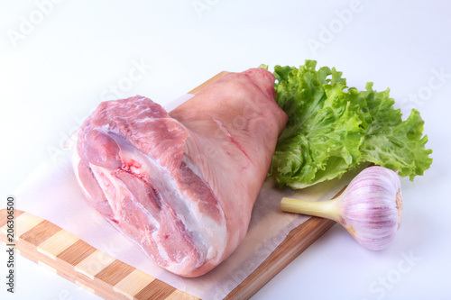 Photography Raw pork knuckle, garlic and lettuce leaves on a cutting board