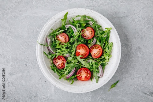 Green salad arugula with tomatoes and red onion in bowl