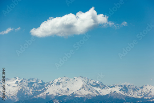 Mountains with peaks covered with snow, white clouds on blue sky, Caucasus