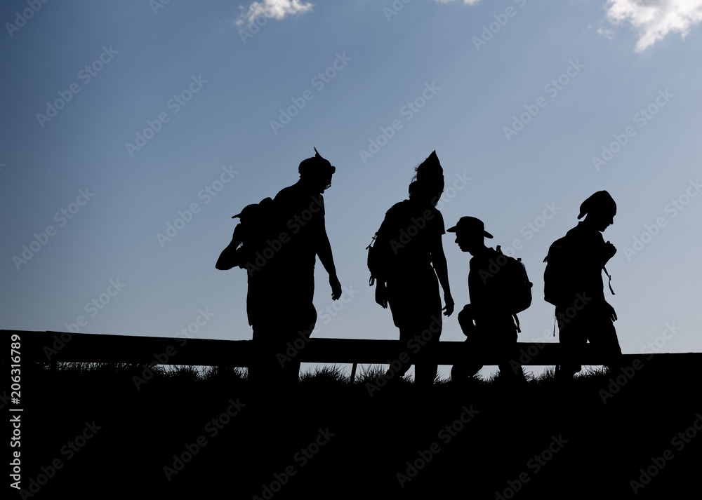 Obraz premium Hikers silhouettes thru thetop of the mountain over blue sky background 