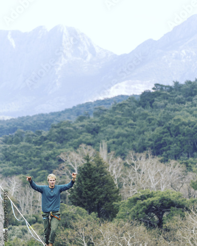 Highliner on a rope. Highline on a background of mountains. Extreme sport on the nature. Balancing on the sling. Equilibrium at altitude.