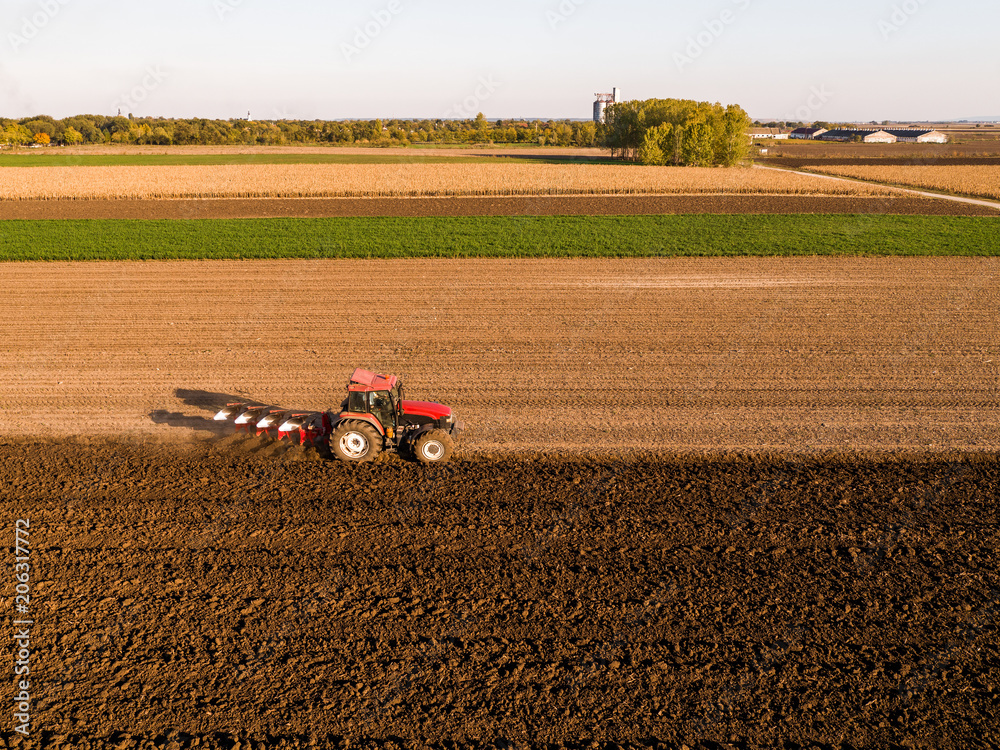 Obraz premium Aerial shot of a farmer plowing stubble field
