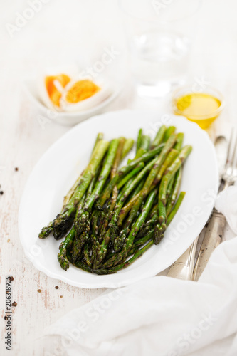fried asparagus on white dish on white wooden background