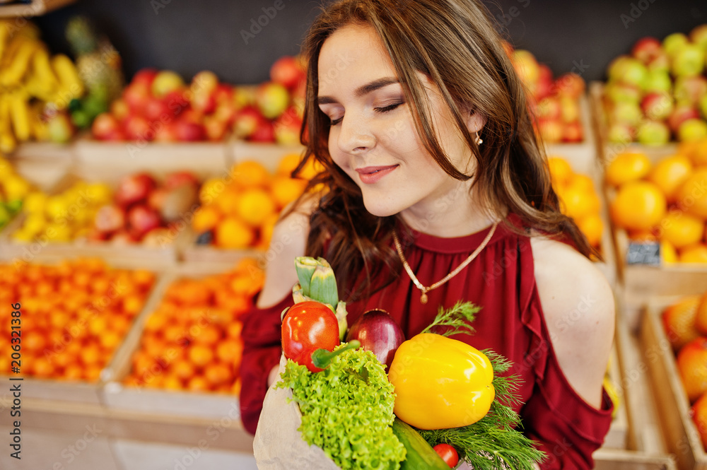 Girl in red holding different vegetables on fruits store. Girl in red holding different vegetables on fruits store.