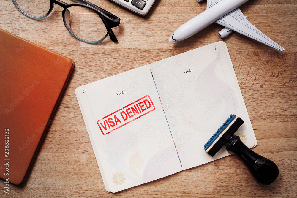 visa and passport with denied stamp on a document top view in