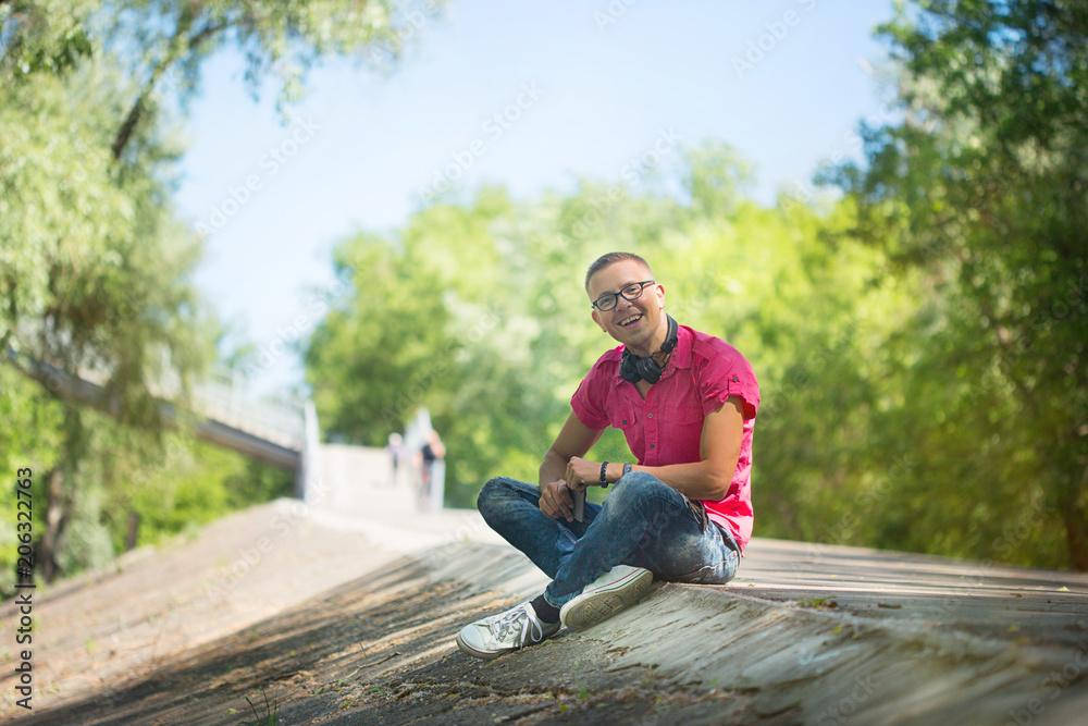 Cute emotional man with headphones wearing glasses in a pink shirt, walking with the phone. Selfie. the man is talking on the phone Cute emotional man with headphones wearing glasses in a pink shirt, walking with the phone. Selfie. the man is talking on the phone