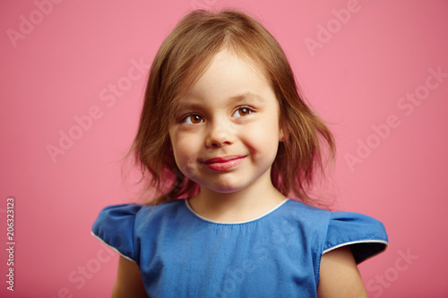 Cute little girl is looking above the camera with a wistful glance.