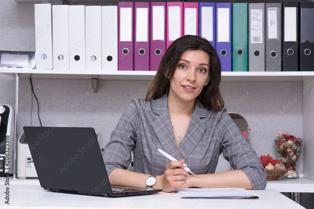 Portrait of a beautiful female manager in the office with a laptop with a visitor. Portrait of a beautiful female manager in the office with a laptop with a visitor.