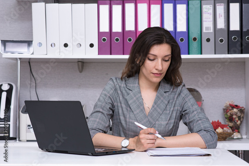 Portrait of a beautiful female manager in the office with a laptop with a visitor.