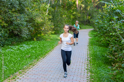 Running girl atletic spotsman trains in the summer park. Outdoor fitness portrait photo