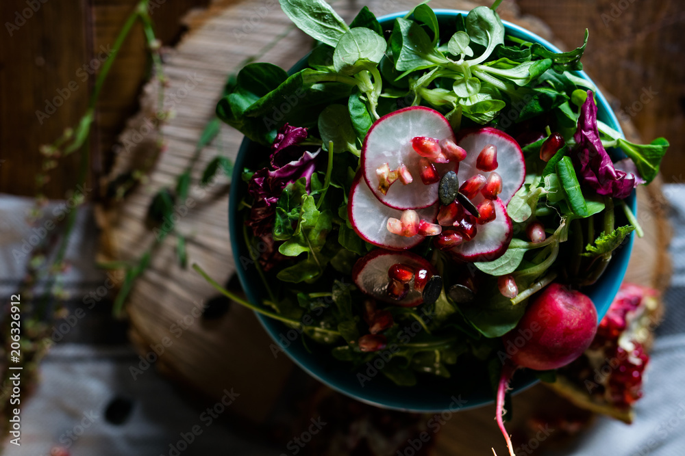 Rustic bowl of lettuce with radish and pomegranate