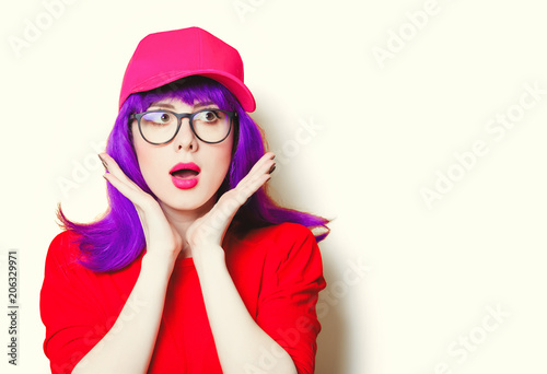portrait of beautiful surprised young woman in cap and glasses
