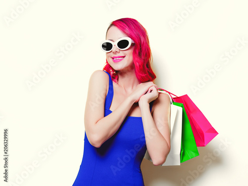 Young pink hair girl in blue dress with colored shopping bags.
