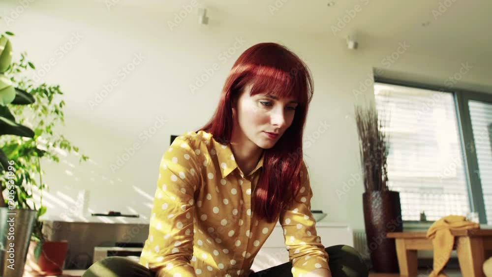 Young woman sitting on the floor at home, working. Young woman sitting on the floor at home, working.