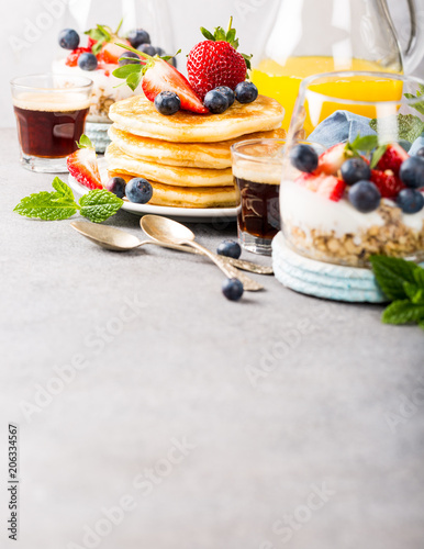 Breakfast background with fresh pancakes and berries on light gray concrete table. Healthy food concept with copy space.