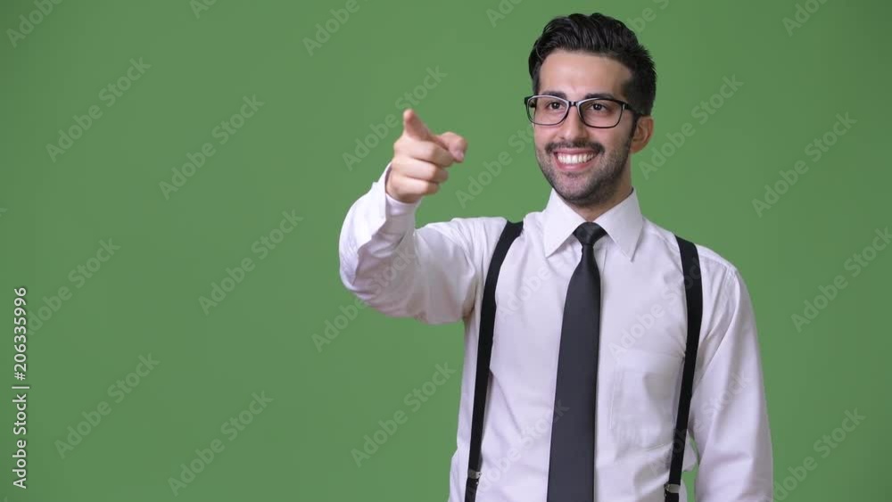 Young handsome bearded Persian businessman against green background Young handsome bearded Persian businessman against green background