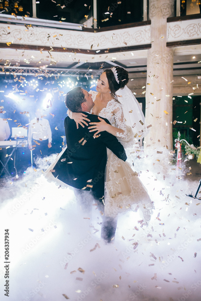 First wedding dance of newlywed. Amazing dancing bride and groom on low light and heavy smoke. A lot of confetti.