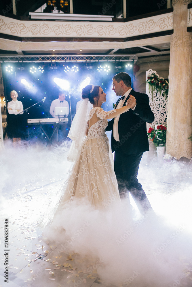 First wedding dance of newlywed. Amazing dancing bride and groom on low light and heavy smoke. A lot of confetti.
