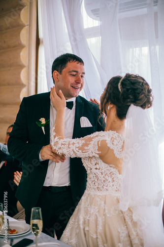 Newlywed Couple Cheerful Wedding Reception. Bride and groom kiss near wedding table. Listening congratulations. 