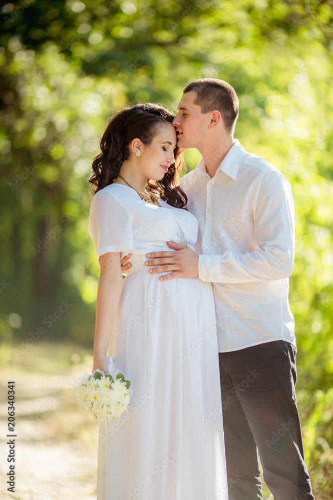 Beautiful pregnant woman with her husband in green garden Beautiful pregnant woman with her husband in green garden