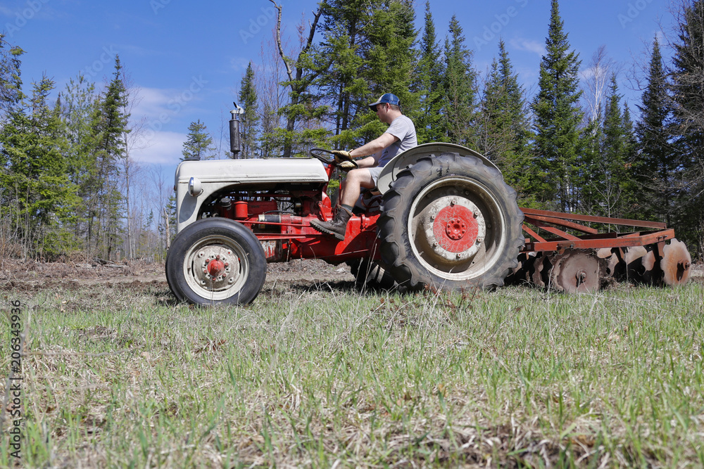 Side view of a man driving a tractor in a field. Side view of a man driving a tractor in a field.