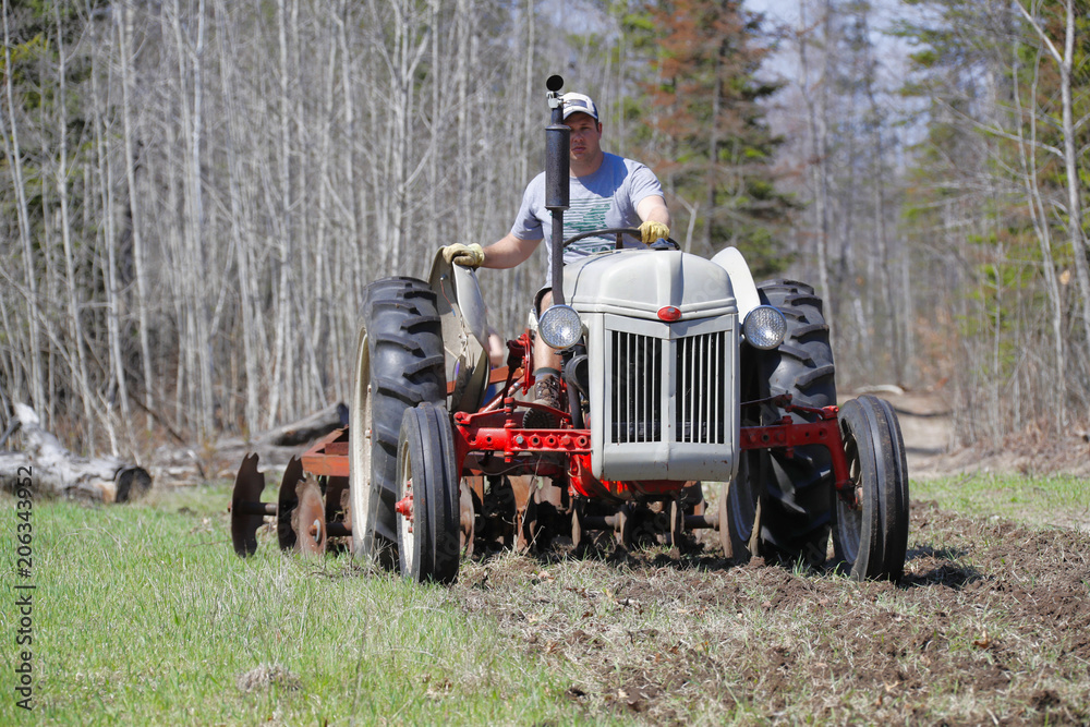 Obraz premium A man driving a tractor to disk a field.
