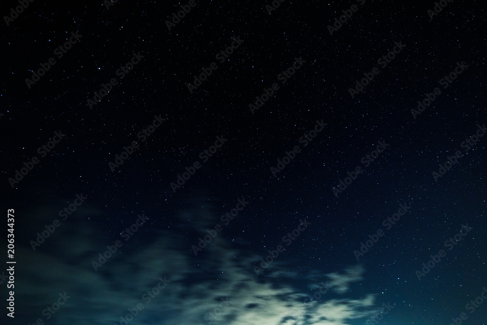 Naklejka premium Starry sky and illuminated clouds.