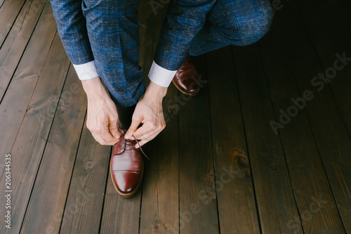 Man wearing a blue suit putting his brown shoes on. Hands and shoe close-up
