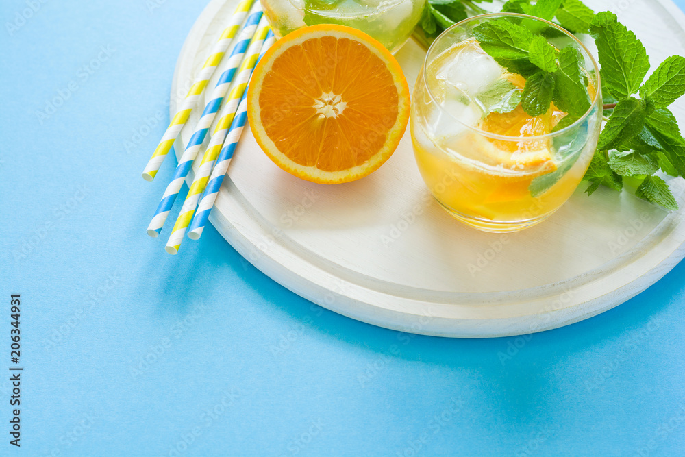 Orange lemonade with slices of orange, ice and mint on blue background. Orange lemonade with slices of orange, ice and mint on blue background.
