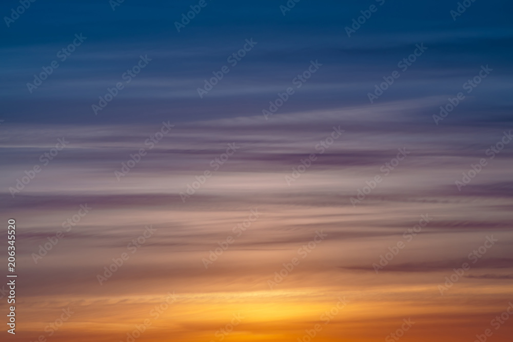 Varicolored striped dawn sky with shades of blue, cyan, cobalt, pink, purple, magenta colors. Horizontal lines of picturesque clouds. Atmospheric background image of warm sky.