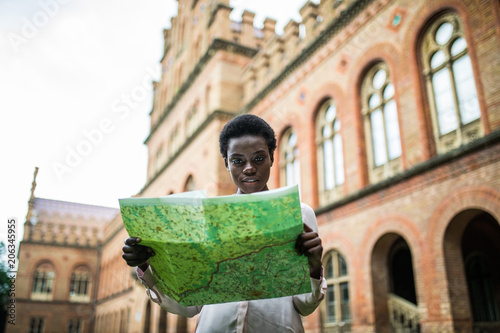 Obraz na płótnie Young attractive afro american female tourist strolling on city streets with map searching right direction to popular showplaces