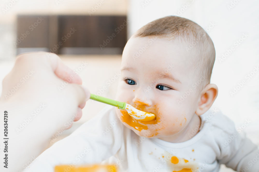 baby with blue eyes eating pumpkin puree all smeared and drenched baby with blue eyes eating pumpkin puree all smeared and drenched