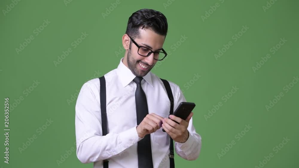 Young handsome bearded Persian businessman against green background Young handsome bearded Persian businessman against green background