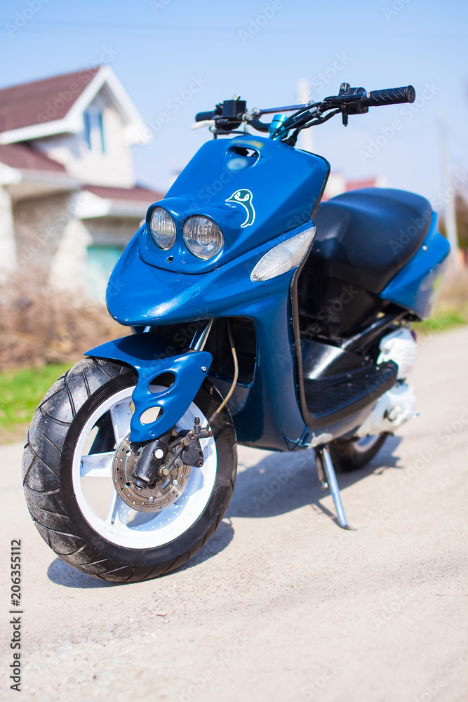 Blue modern scooter on the gravel road front view