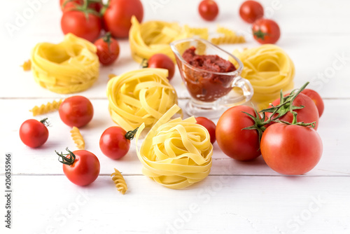 Pasta Products with Tomato Cheese Raw Pasta Fusili Fettuccine Ingredients Italian Food White Background Close Up Copy Space