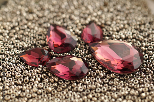 Shiny burgundy crystal rhinestones and metallic seed beads closeup background