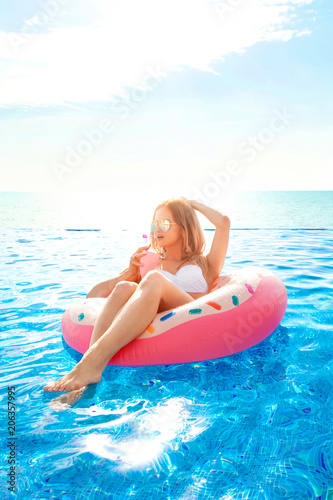 Summer Vacation. Woman in bikini on the inflatable donut mattress in the SPA swimming pool.