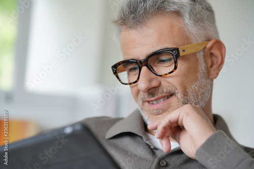 Smiling middle-aged man connected with tablet
