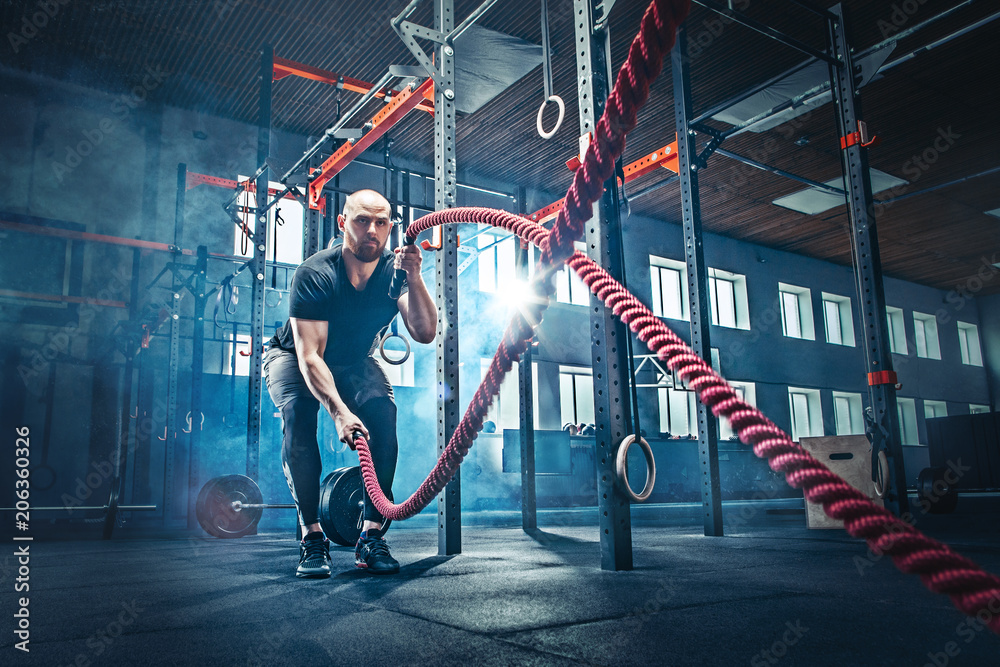 Men with battle rope battle ropes exercise in the fitness gym