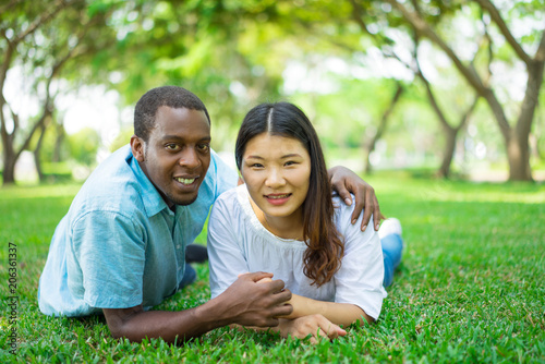 Smiling Asian woman and African American man lying on grass