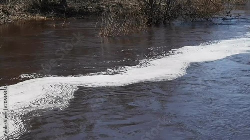 Plume of foam floating on rapid river. Result of water pollution
 photo