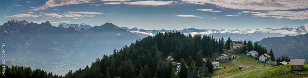 panorama view of a mountain landscape in the Swiss Alps with huts and chalets in the foreground