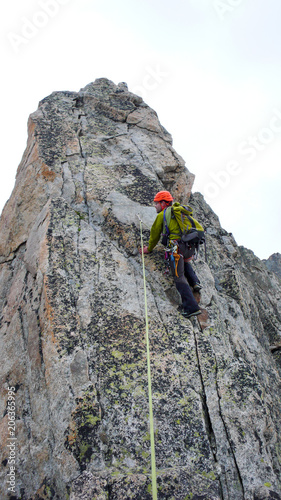 male mountain guide lead climbing on an exposed granite ridge in the Alps