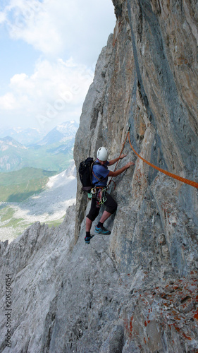 male mountain climber on a steep rock climbing route in the Swiss Alps near Klosters