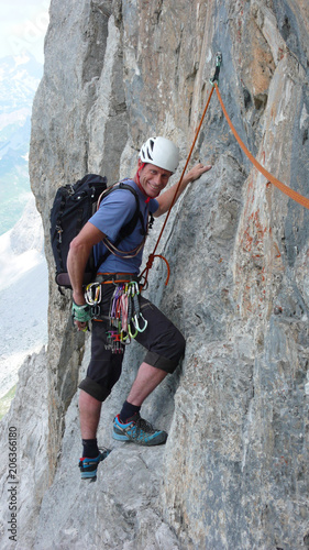 male mountain climber on a steep rock climbing route in the Swiss Alps near Klosters