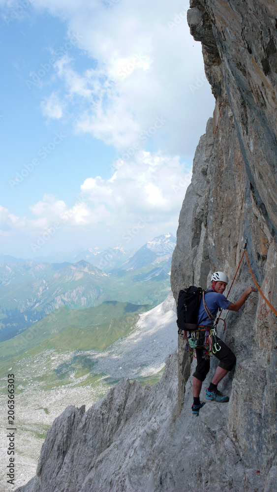 male mountain climber on a steep rock climbing route in the Swiss Alps near Klosters